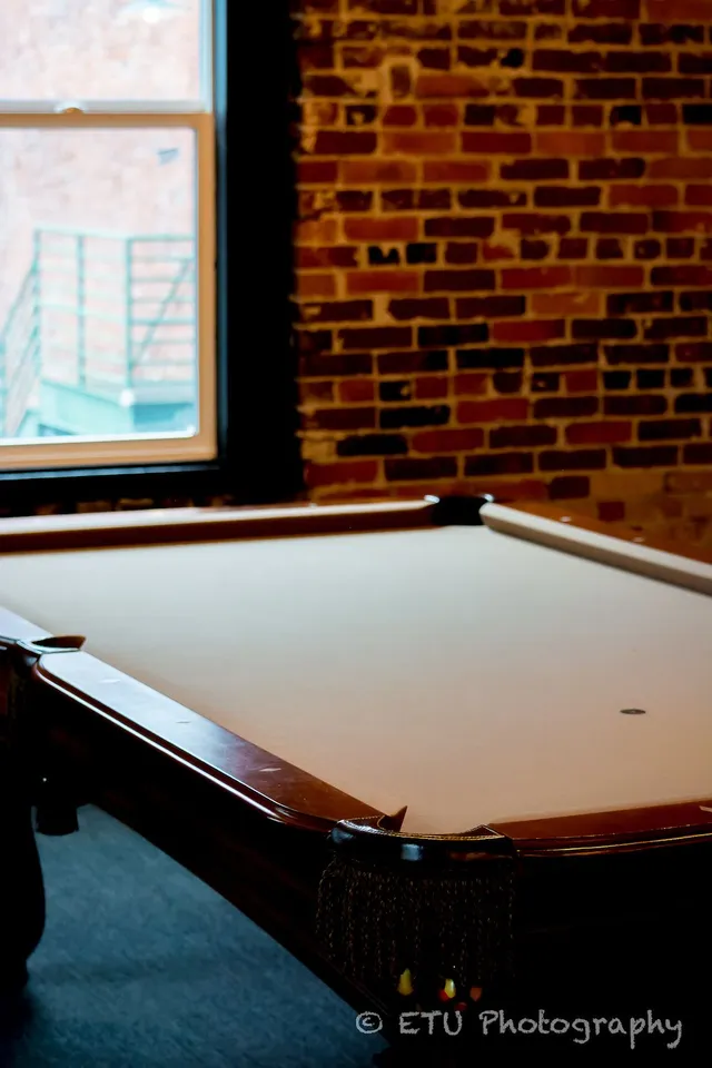 Pool table with brick wall and window